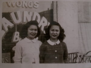 Two young sisters in front of family laundry.