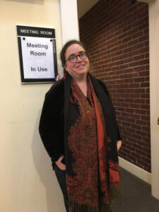 Tanya March standing in from of sign that says "Meeting Room In Use"