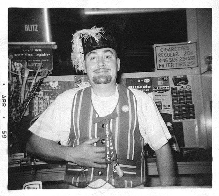 George Beesaw Feb 14, 1959 in a fuze hat and a striped vest the price of cigerattes being sold behind is so low as to be distracting 25center