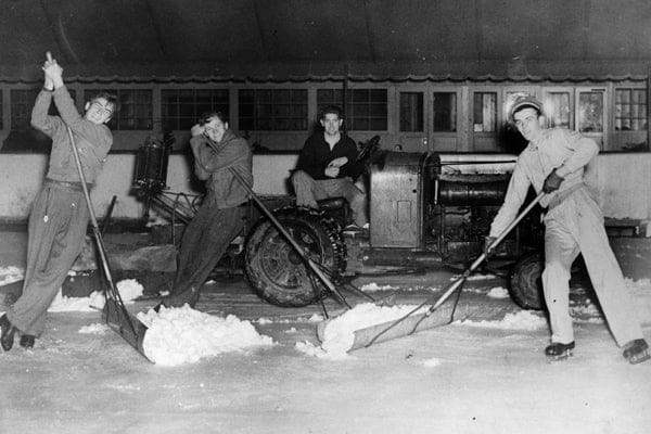 Men using shovels to scrap loose ice off of a artifical  ce surface.