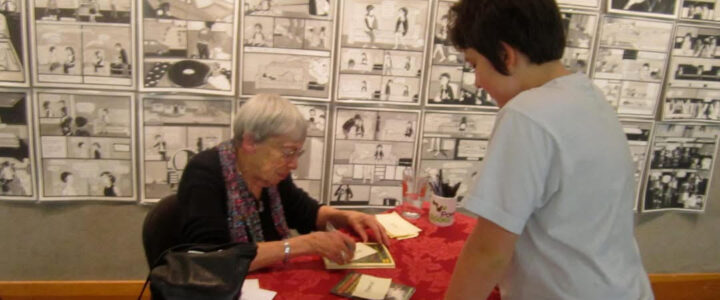 Ursula is signing a copy of Cat Wings for Brooklyn at Powells Books there are dozens of black and white pages pined to the wall behind them