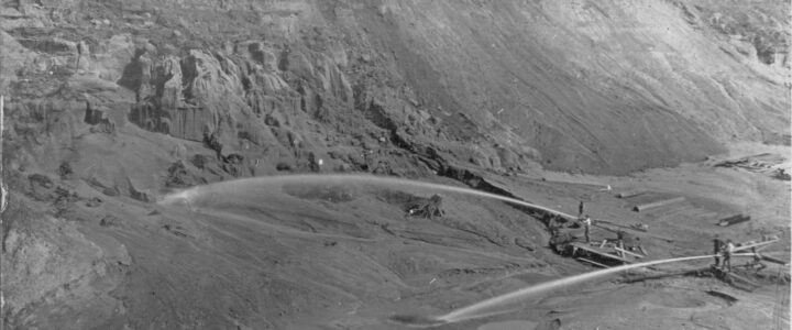 Image of a 100' tall 80' ditch being created by two high pressure water blasts in operation. People look like ants in this image.