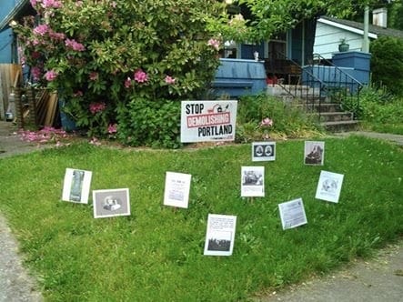 Nine laminated 8.5"x11" images stuck into a front yard lawn with chopsticks- a political lawn sign with the words Stop Demolishing Portland