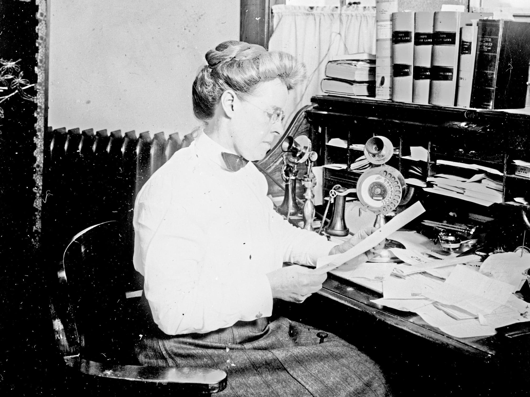 Lola Green Baldwin is about 50 in this picture first police woman at a secretary desk with lots of books papers and a standing antique phone