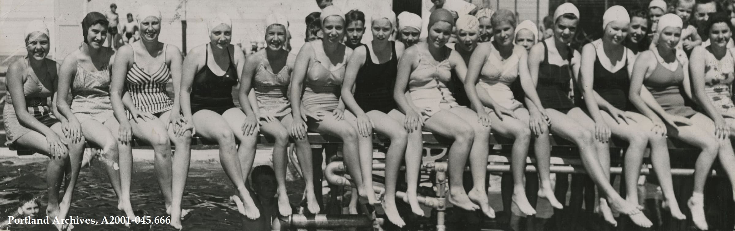 Row of woman in bathing suits and bathing caps. Its a vintage image so bathing suits are all one piece. Image is B&W