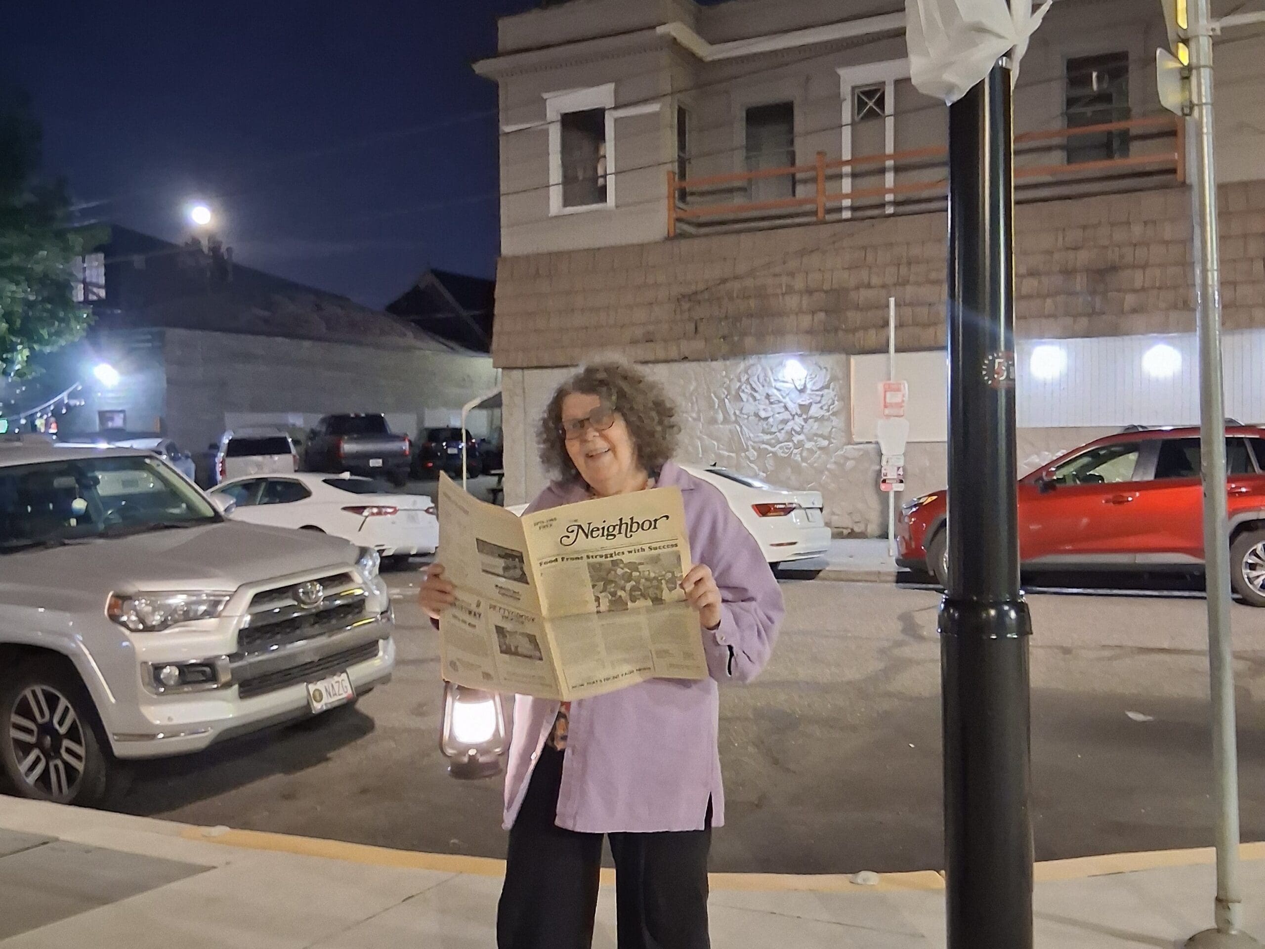 A run down dive bar with a yellow sign Joe's Cellar is behind. There is a balcony were women once sold sex to those existing the area. Second floor of the building is vacant. Kathy is a small women faking to be reading a newspaper - she uses a screen reader. She knows that the issue from decades ago of the neighbor paper has the article about her formers home's ghost.