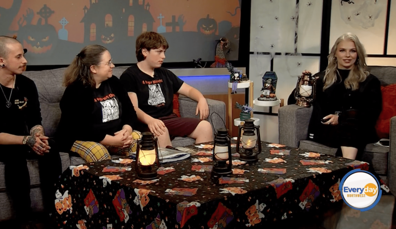 There are three people on a sofa on the right (L-R) Josh cool punk guy with tattoos, Tanya March 53 year old lady with plaid yellow pants and a branded t-shirt, Berkeley a Roosevelt High school student, lots of Brooklyn lamps and halloween decorations, Host is a glamorous blond holding a lantern all in black