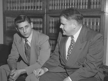 1951 Killer with lawyer cleaned up for trial. There are shelves full of law books on full shelves