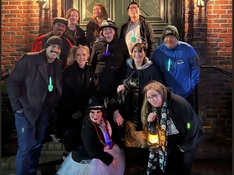 Nine guests and Tanya posing for a picture folding lanterns some guests are wearing glowsticks.