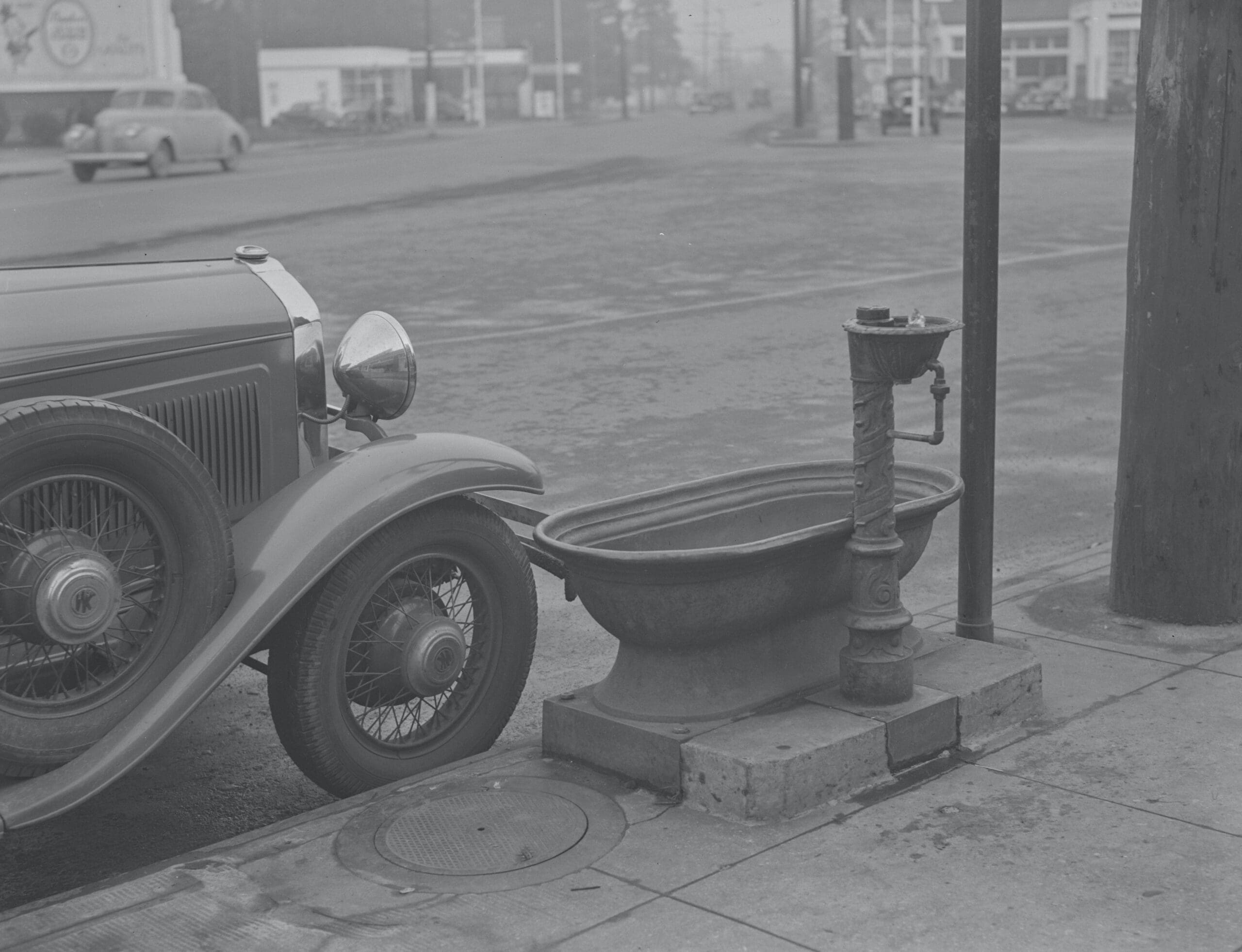 House trough & with a human fountain next to a 1940s car B&W