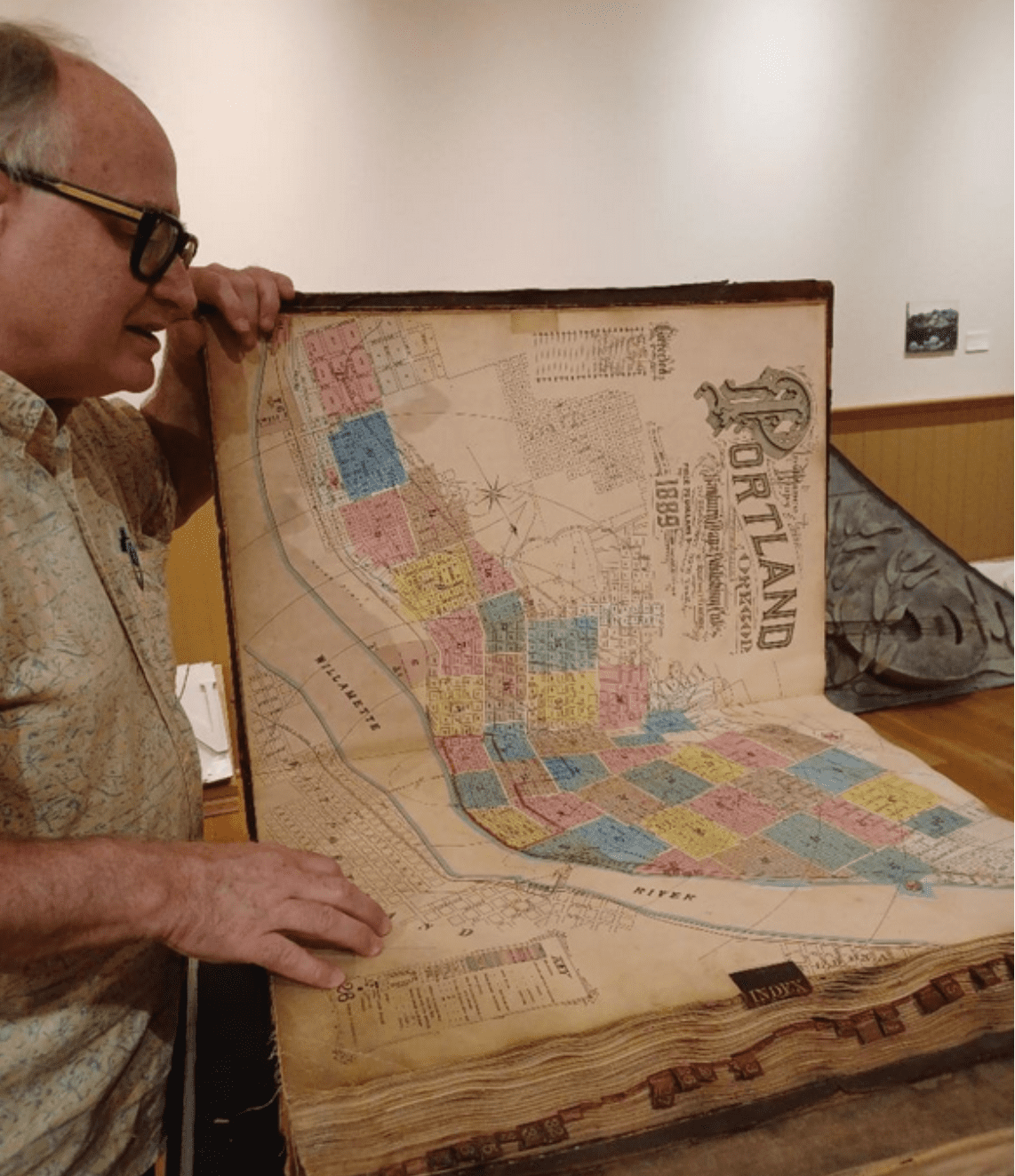 Norman in his sixties with cool glasses turning the pages of a Sanborn