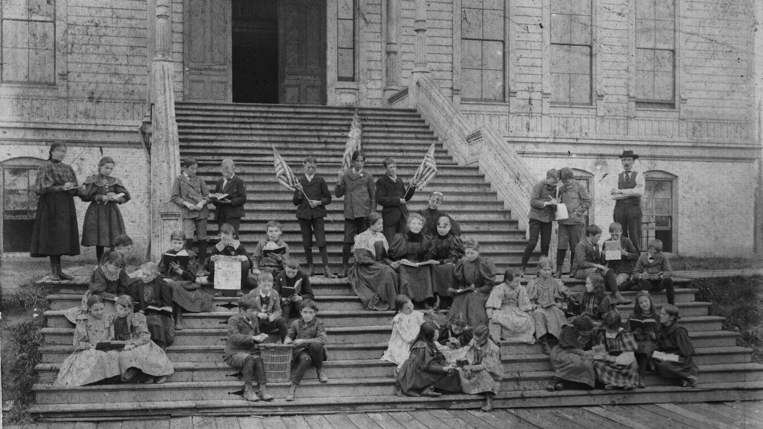 11-8-1896-Miss SpencerClass Norm's collection kids are scattered over the front steps of the school. American flags a trash can is being used as a desk randomness of pose seems really odd